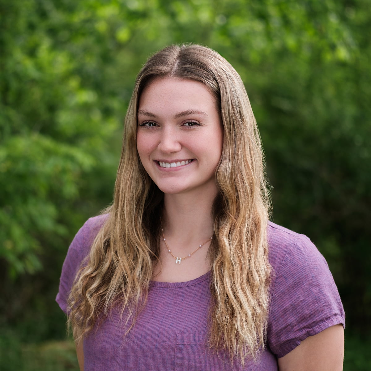 headshot of young woman outside in purple top