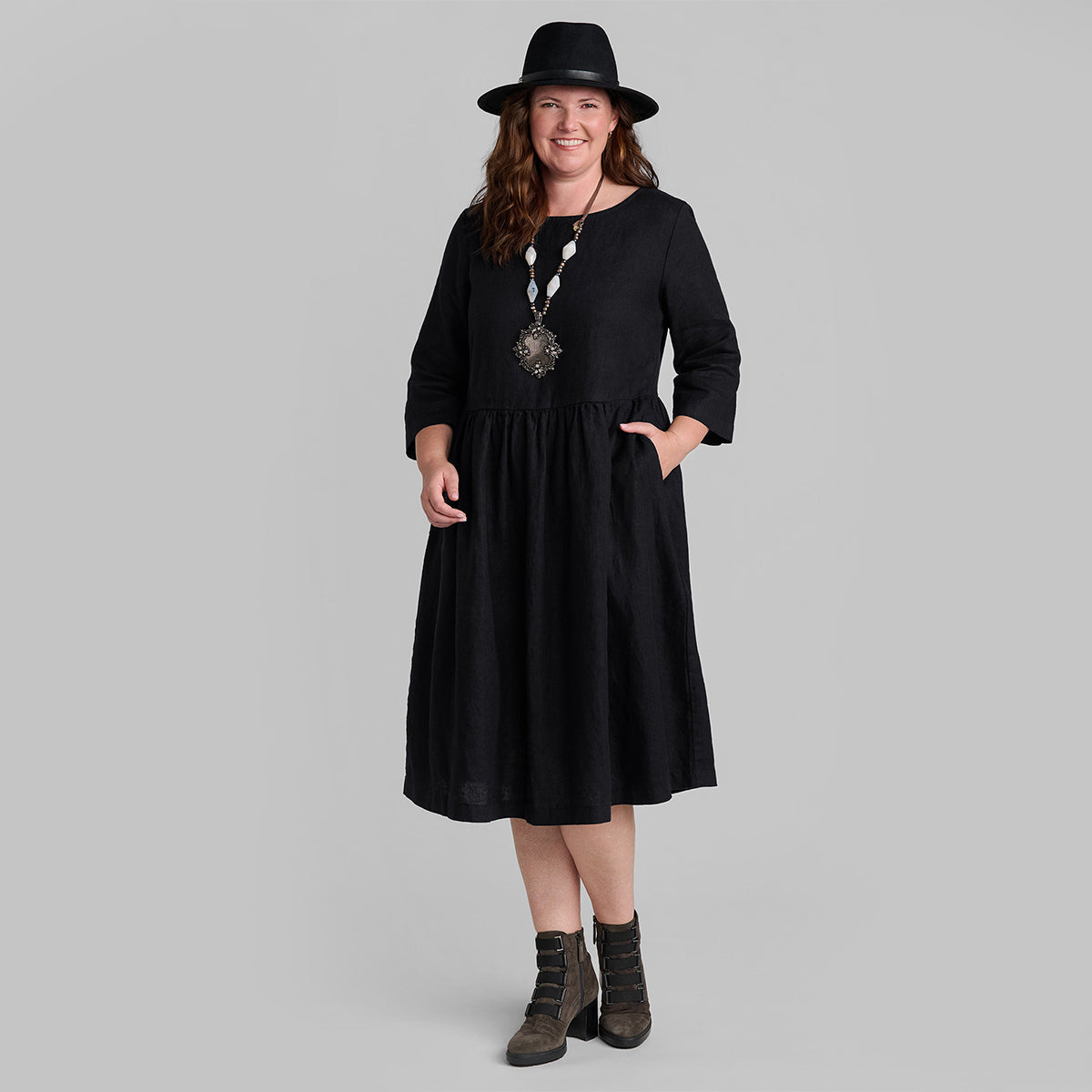 woman wearing black linen dress with boots and a hat