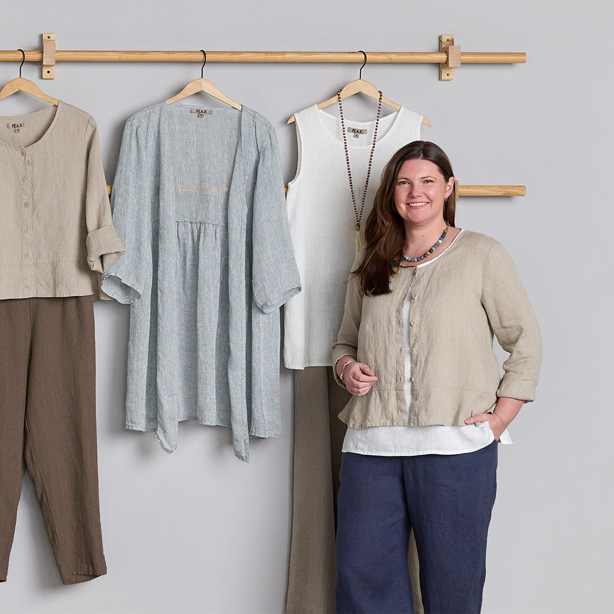 woman wearing FLAX linen clothing in front of a rack of clothes