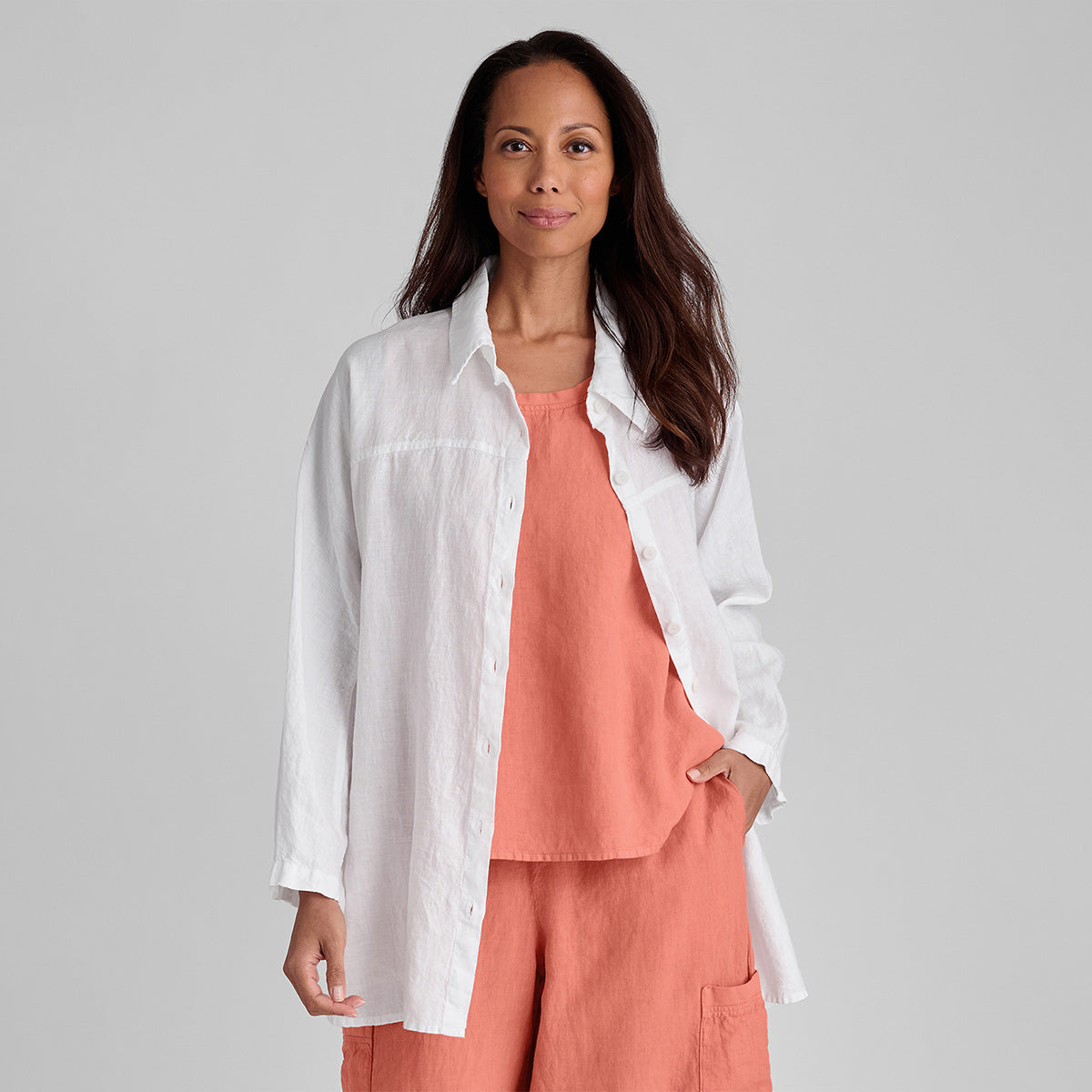 woman wearing a white linen button down shirt over an orange outfit