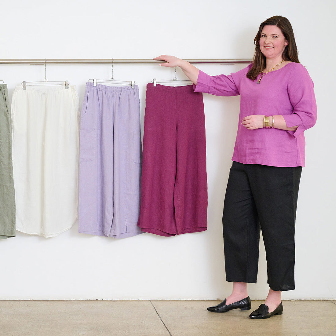 woman standing in front of a rack of pants hanging up