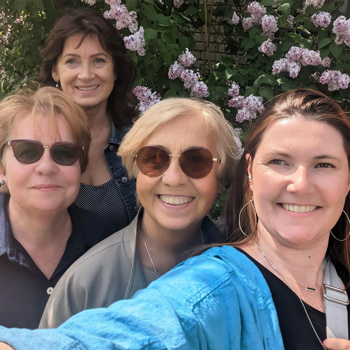 four women smiling outside for a selfie
