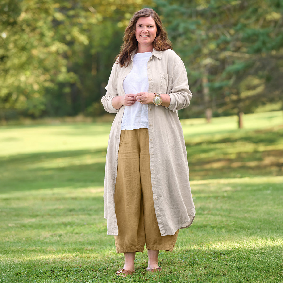 woman outside wearing natural linen shirtdress with white linen tank top and brown linen pants