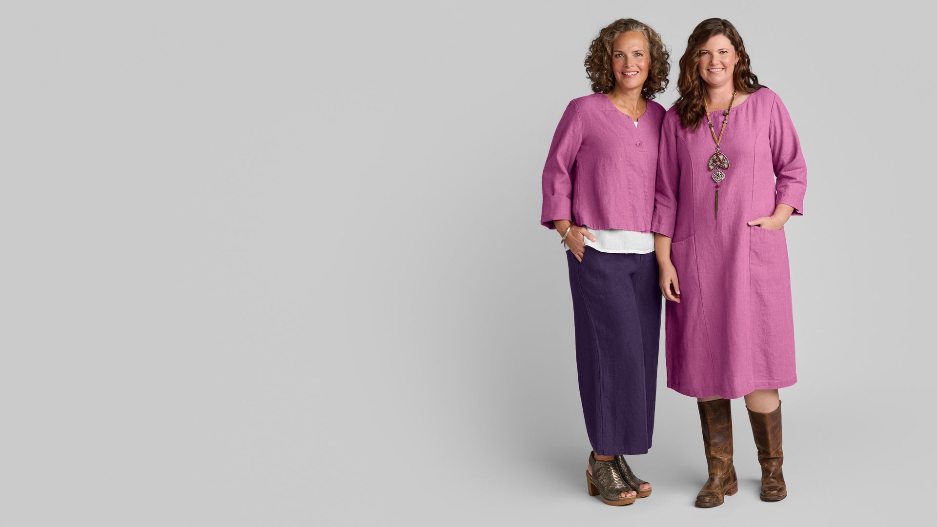 Women in Flax clothing brand linen shirts, pants, and dresses in pink and purple