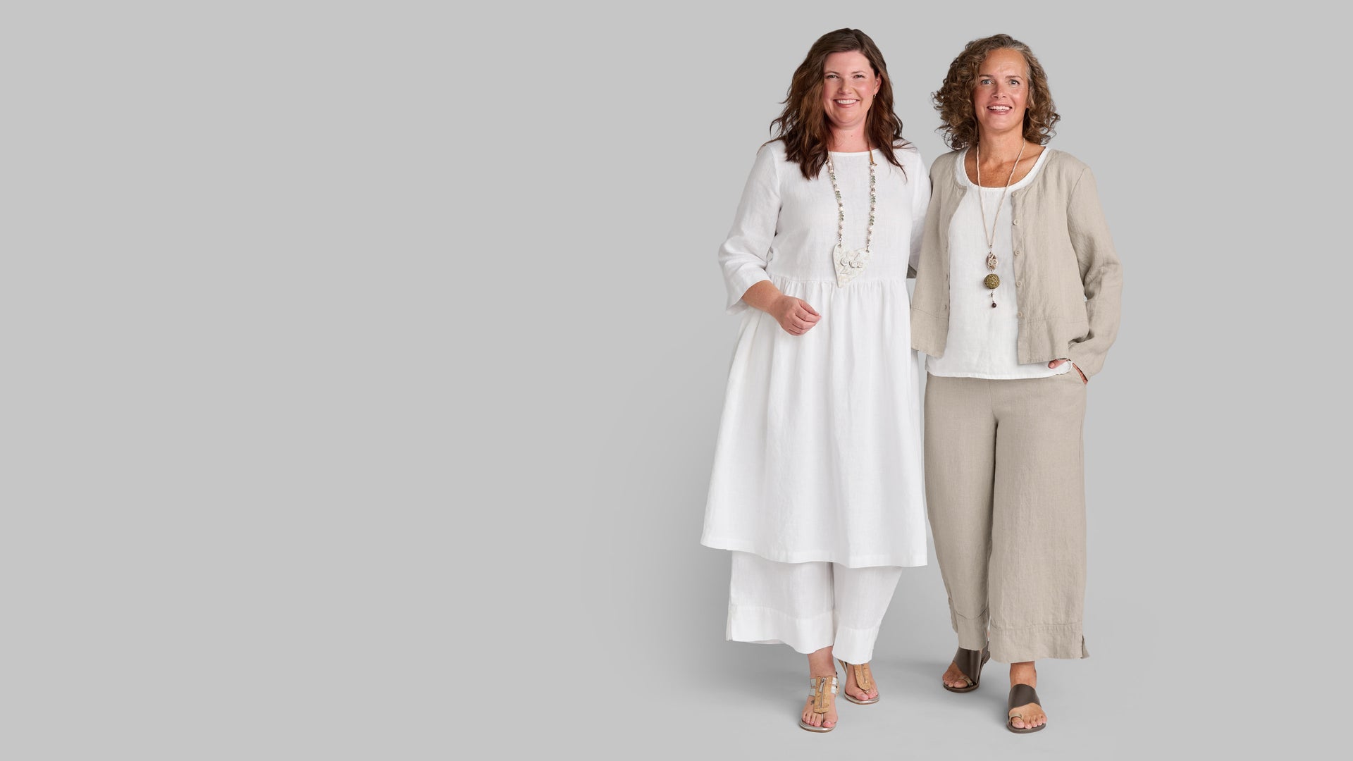 Two women in FLAX women's linen outfits in white and tan