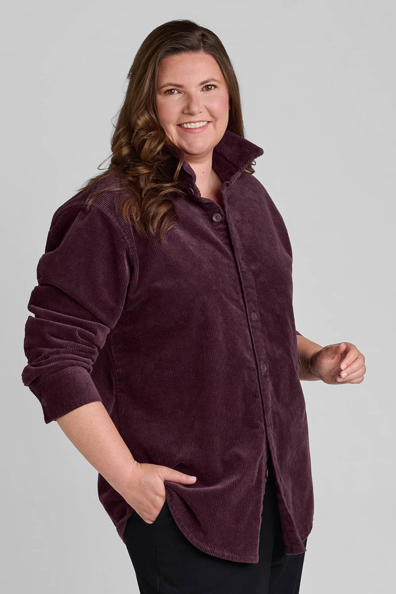 Woman in red corduroy shirt with rolled up sleeves and black pants