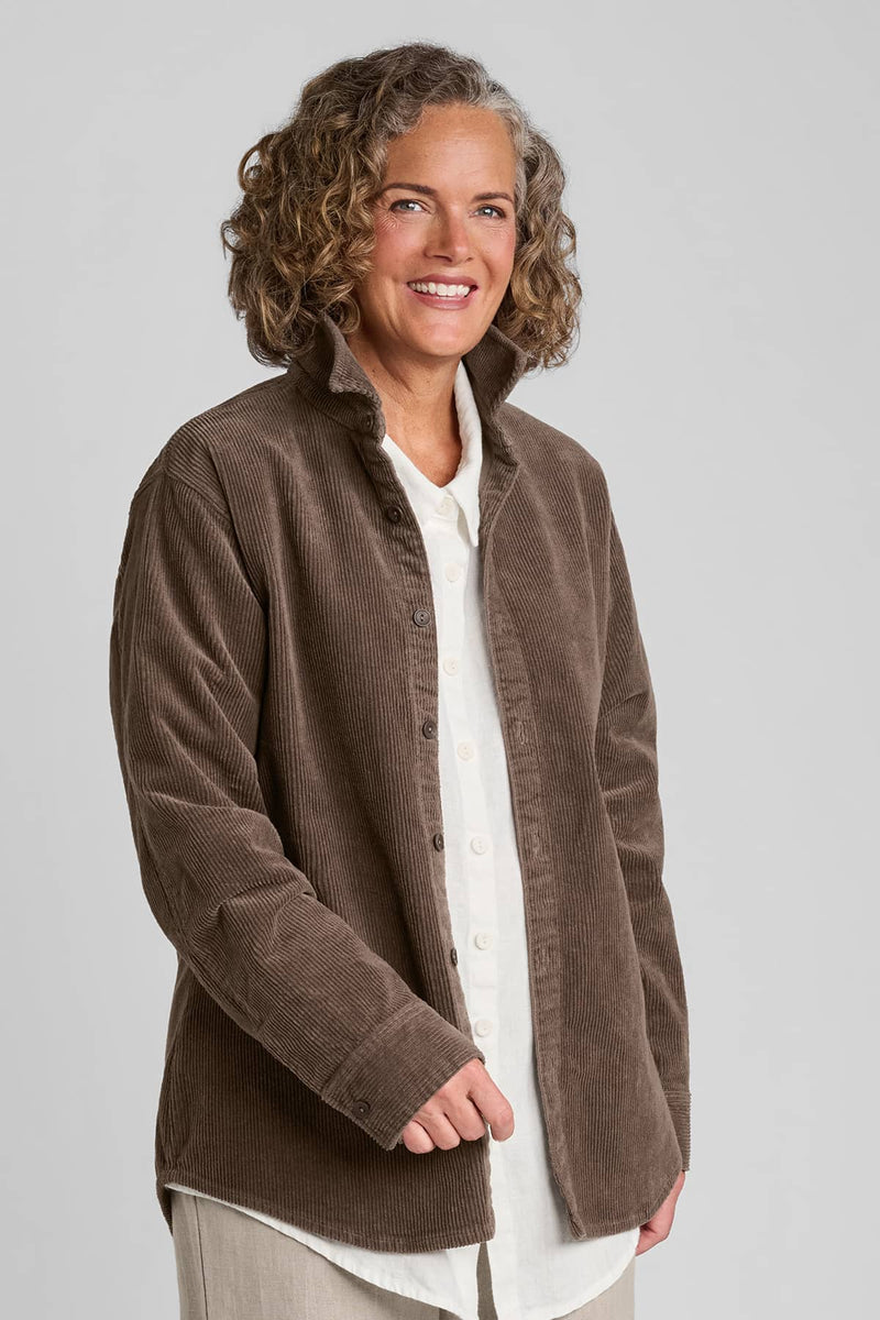 Woman in brown corduroy shirt with white linen blouse underneath and beige linen pants