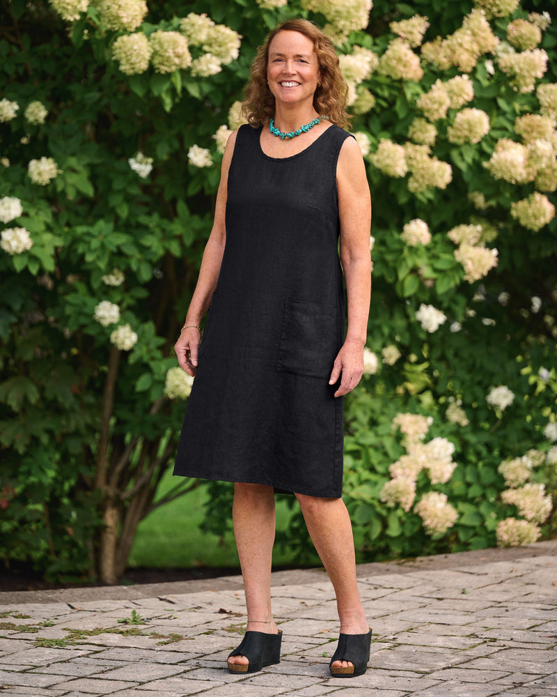 Woman in sleeveless black linen dress with patch pockets