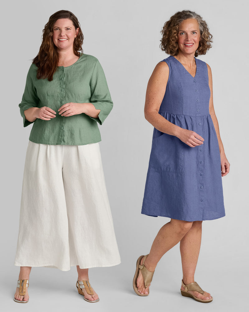 One woman in a green linen shirt and white wide leg linen pants and one woman in a blue linen dress