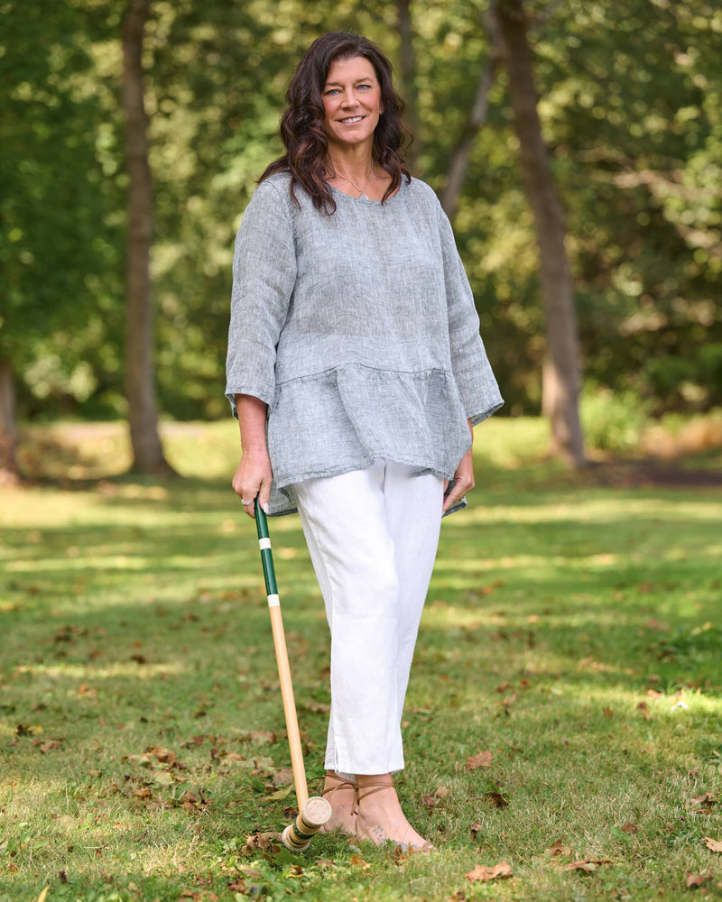 Woman in blue linen shirt with sleeves and tapered white linen pants