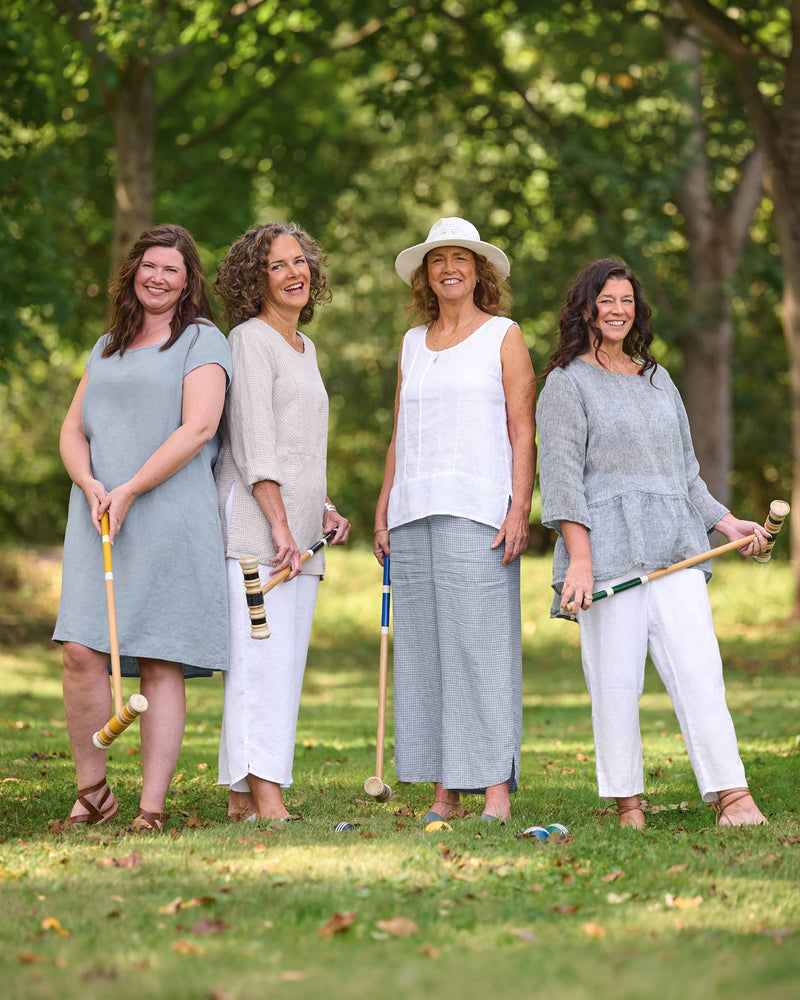 Women in Flax clothing brand blue, white, and natural linen dresses, shirts, and pants