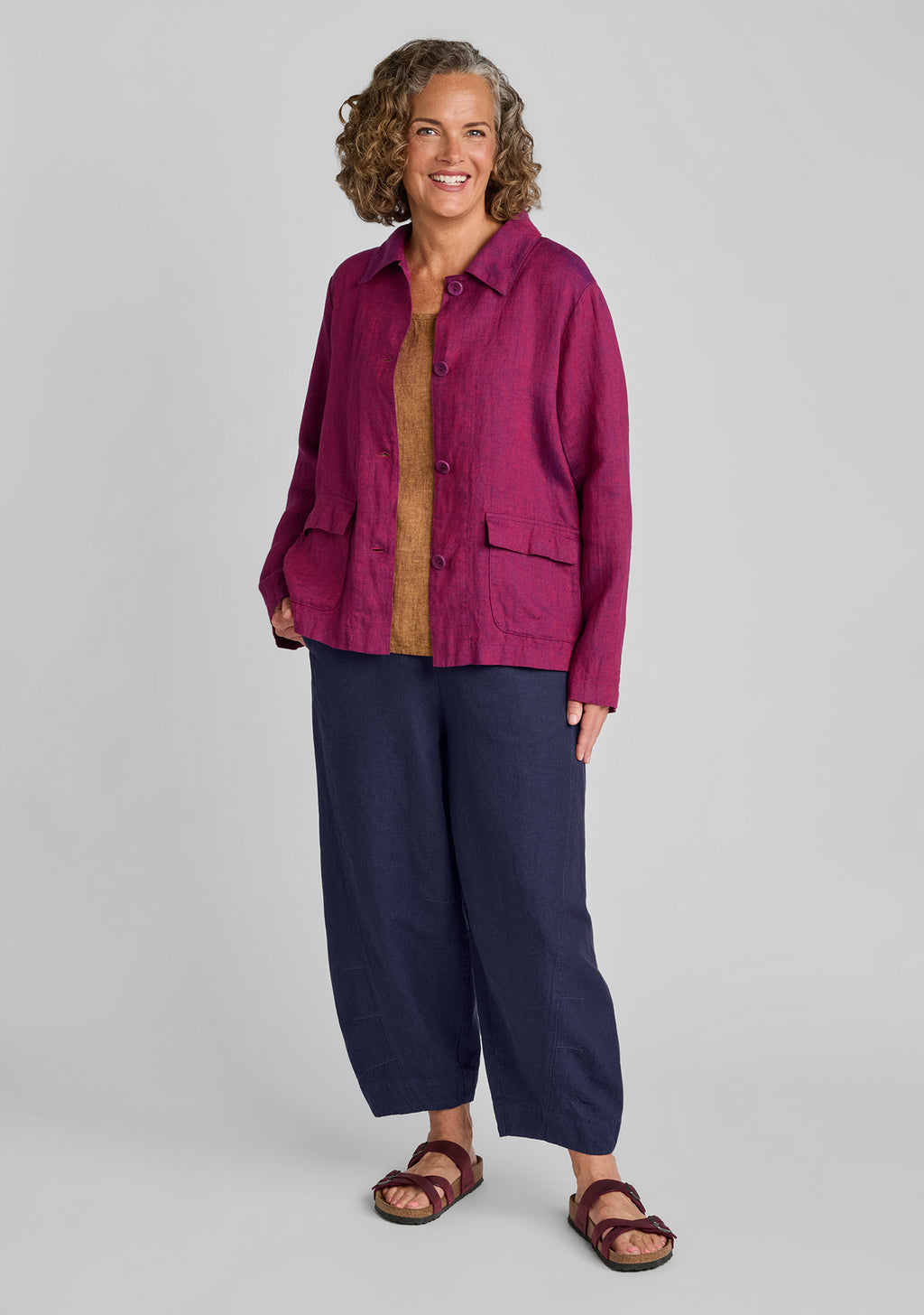 a woman modeling a linen jacket over a tan top and navy barrel pants