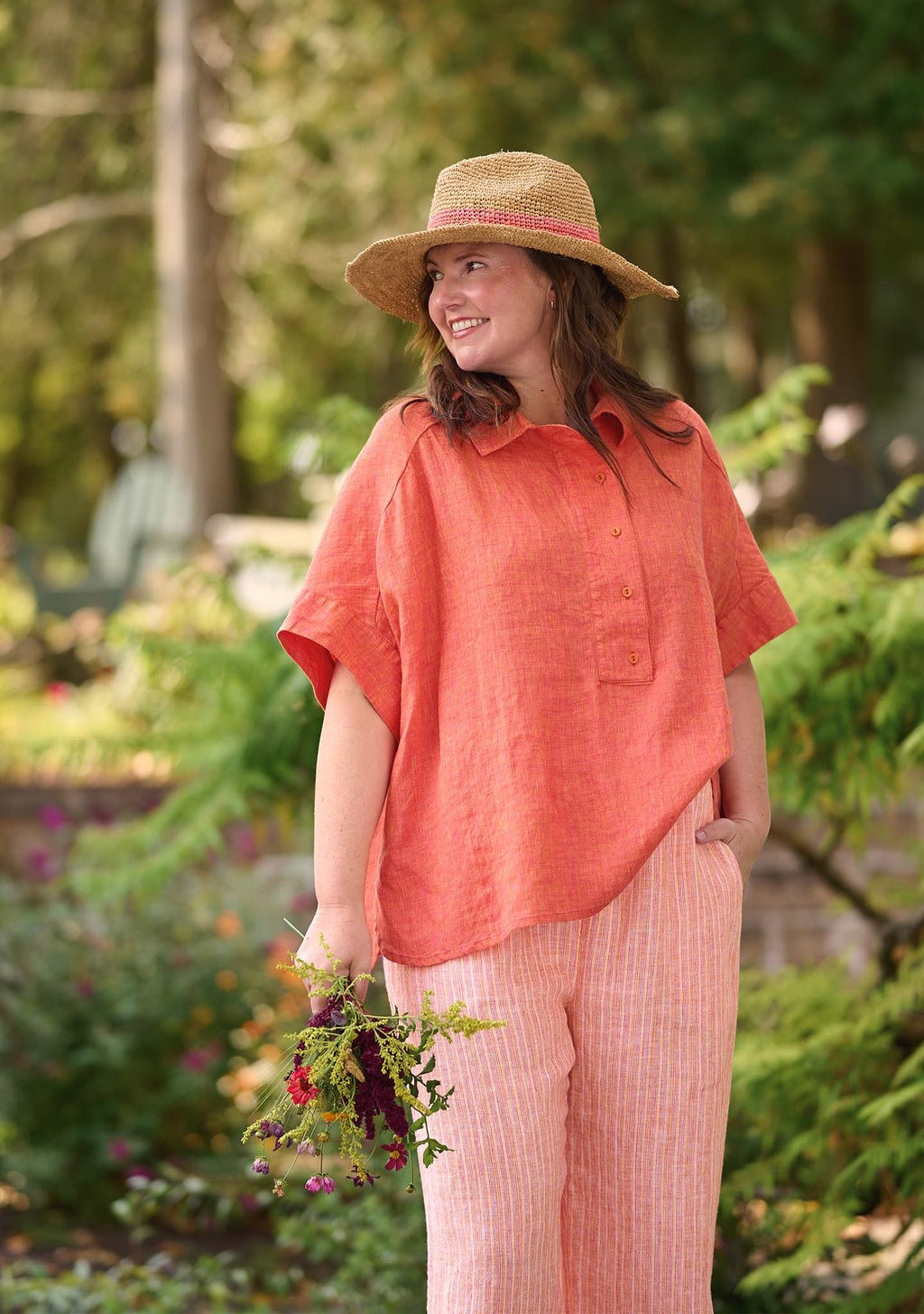 woman outdoors in linen pullover in orange and linen pants in orange stripe