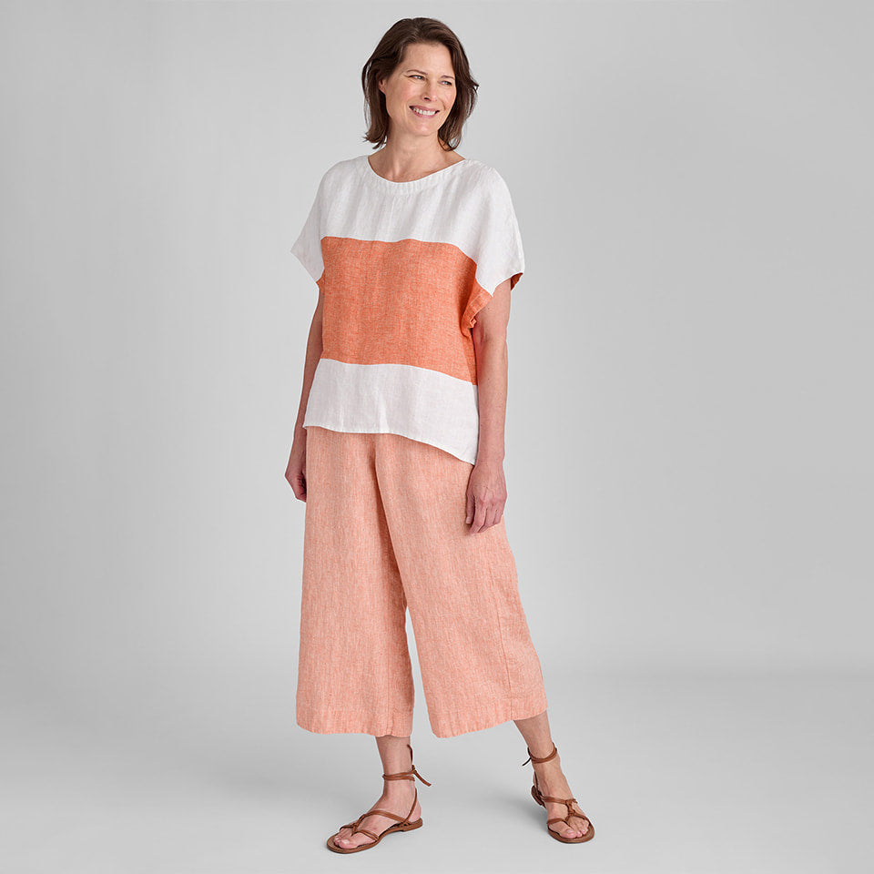 Woman in orange and white striped short sleeve linen shirt and orange linen pants