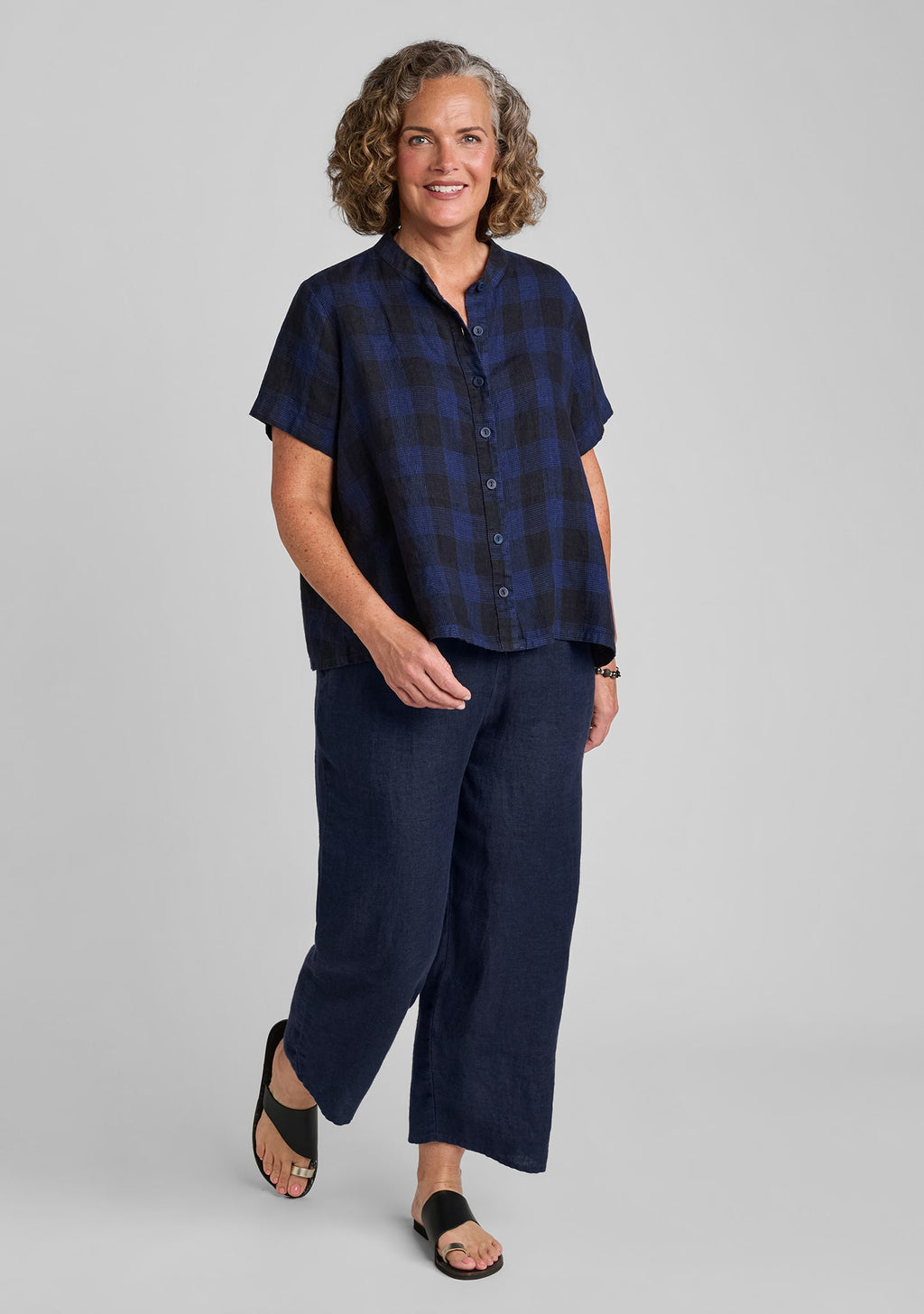 a woman modeling a short-sleeve navy blue plaid button-up shirt and matching navy wide-leg pants