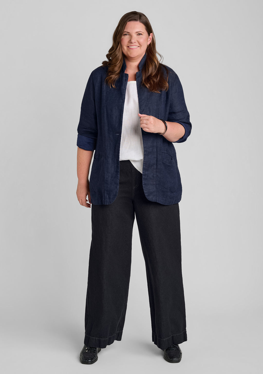 a woman modeling a dark navy blue linen-blend jacket over a white top and black wide-leg pants