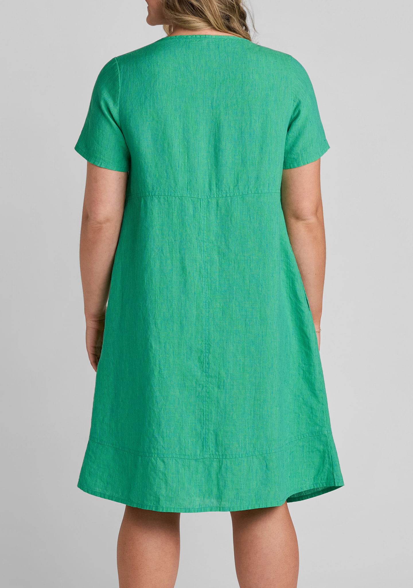 close up view of fabric on the back of women's linen dress in green