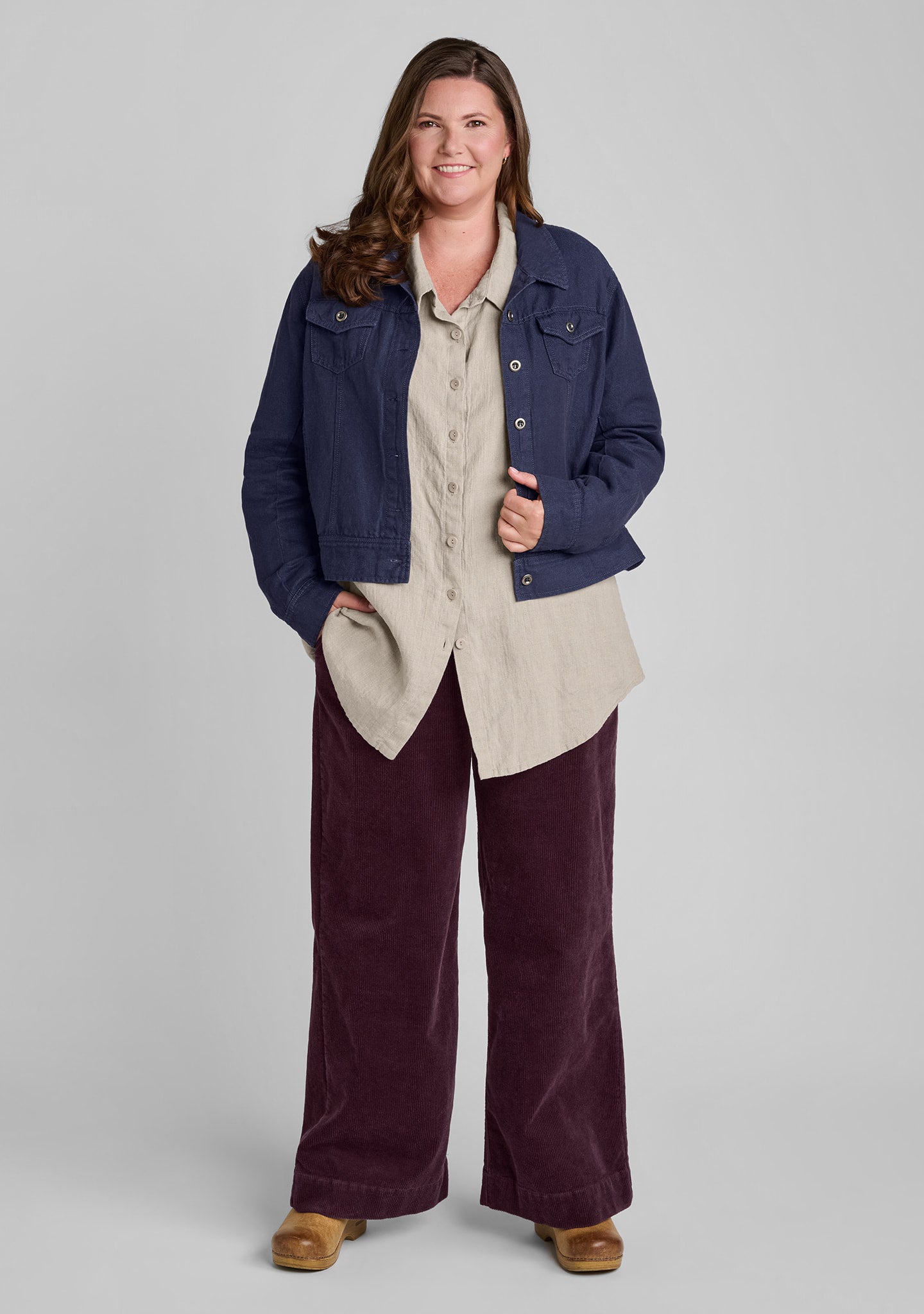woman wearing denim jacket over blouse in natural linen and purple corduroy pants
