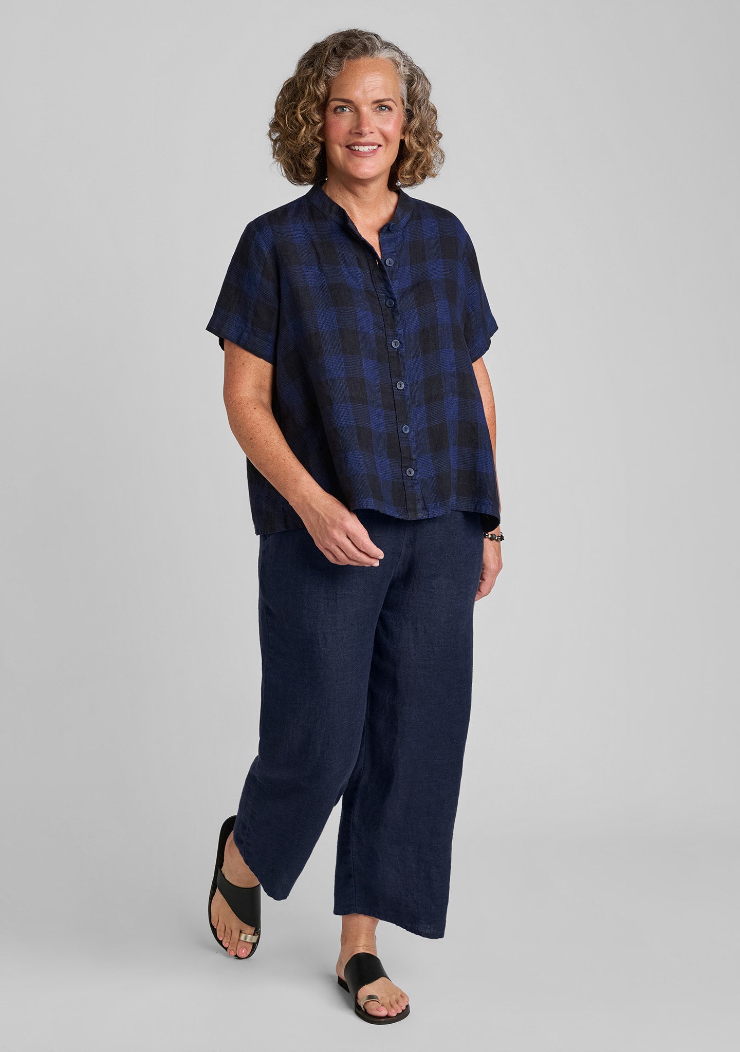 a woman modeling a short-sleeve navy blue plaid button-up shirt and matching navy wide-leg pants