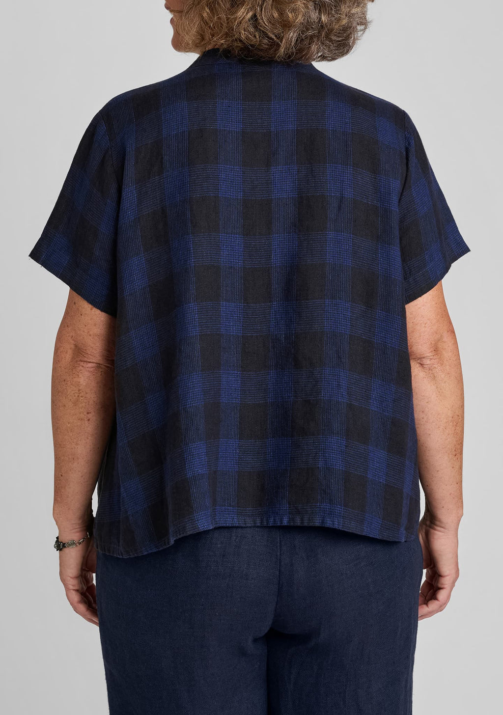 back view of a woman wearing a blue plaid shirt